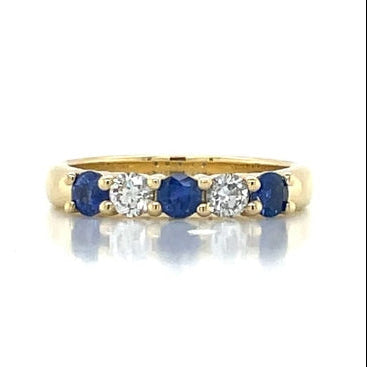Gold ring with blue sapphires and diamonds on a white background