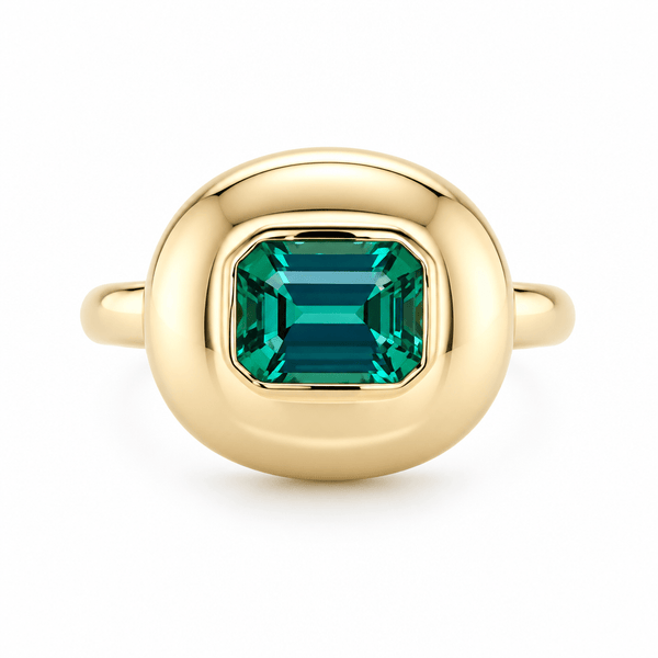 A gold ring featuring a large, cushion-cut emerald-cut green gemstone, presented on a clean white background.